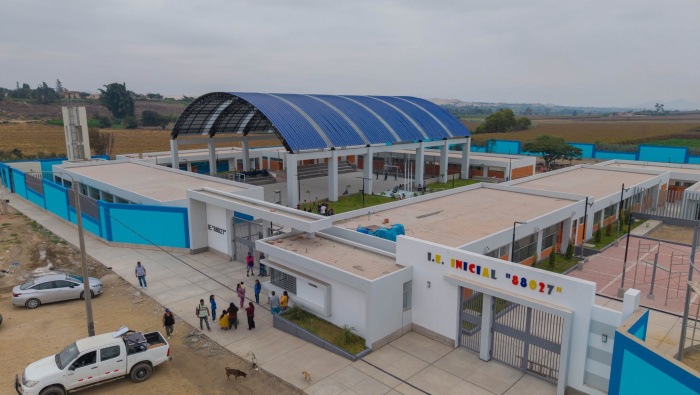 Vista aérea del colegio nuevo de Lacramarca Baja: pabellones blancos, cerco celeste, losa con arco azul y el letrero I.E. Inicial 88027 en la fachada, con campos de cultivo al fondo.