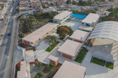 Vista aérea del campus: pabellones blancos con fajas de ladrillo, losas deportivas, cobertura arqueada metálica y cerco perimétrico de ladrillo con paneles blancos.