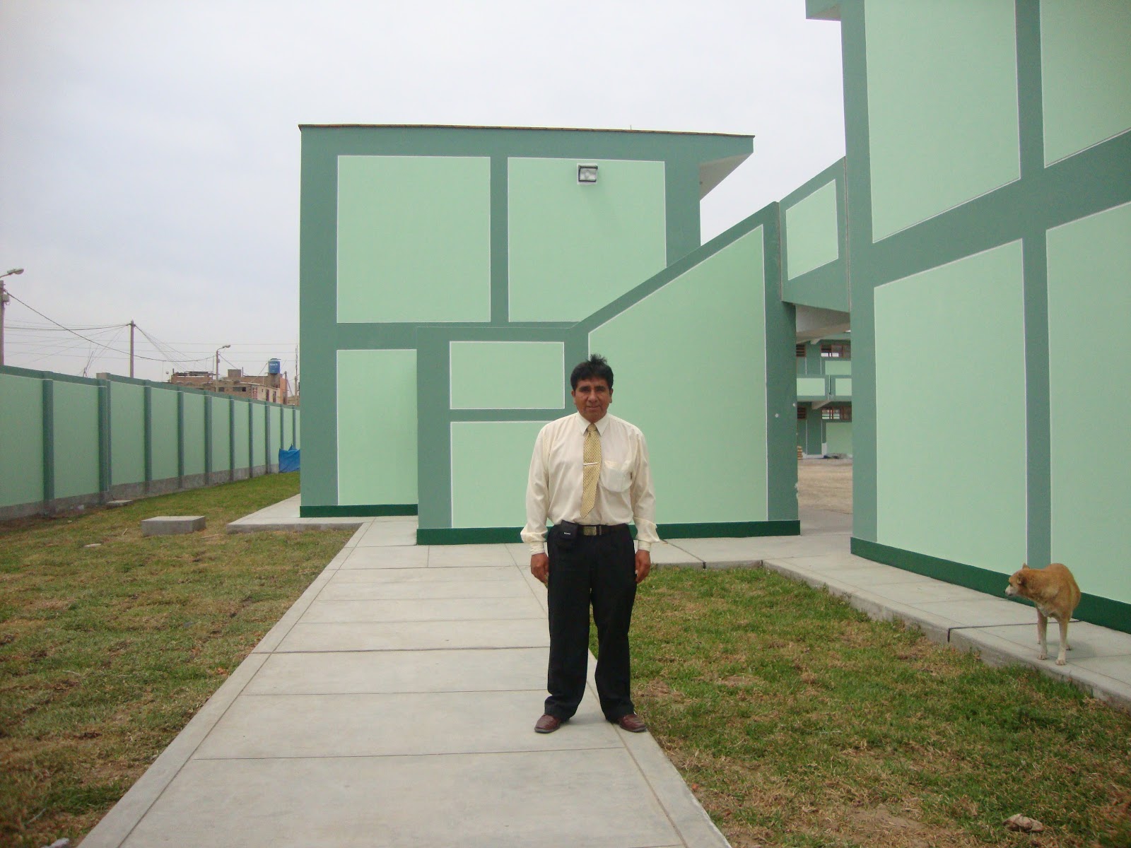 El director Eduardo Bocanegra Gutiérrez posa de camisa clara y corbata en el paseo central del plantel, entre pabellones menta.