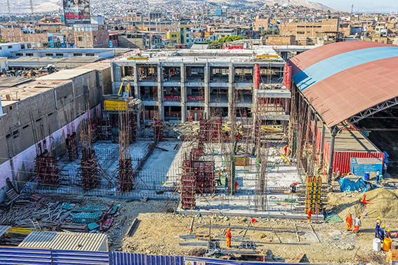 Vista aérea de la obra con el nuevo pabellón de tres niveles en estructura de concreto y columnas con fierro, junto al techo curvo existente.