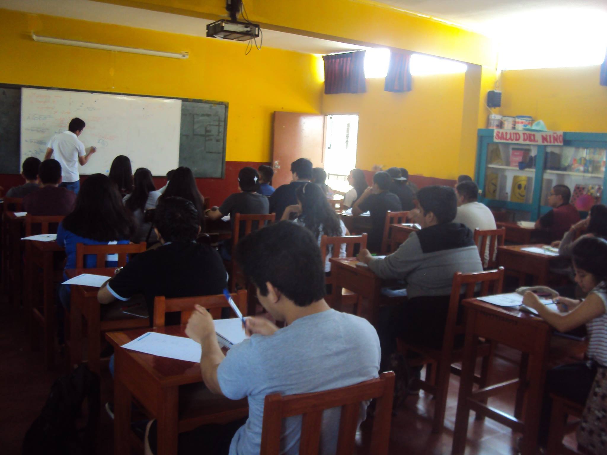 Aula con paredes amarillas y panel Salud del Niño en la Experimental UNS
