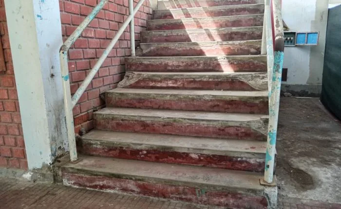 Escalera desgastada dentro de la infraestructura escolar antigua, fotografiada antes de la demolición.