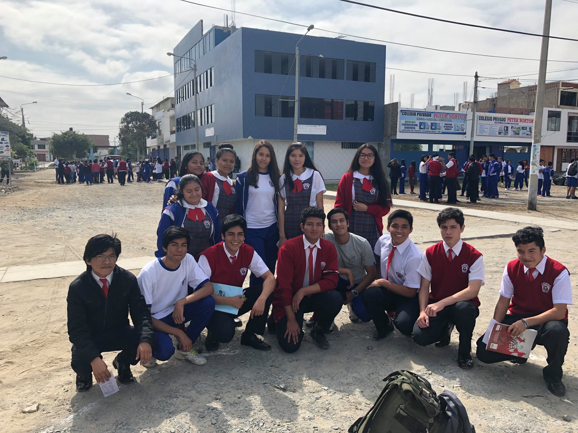 Grupo de estudiantes del colegio Peter Norton frente al pabellón azul con letreros