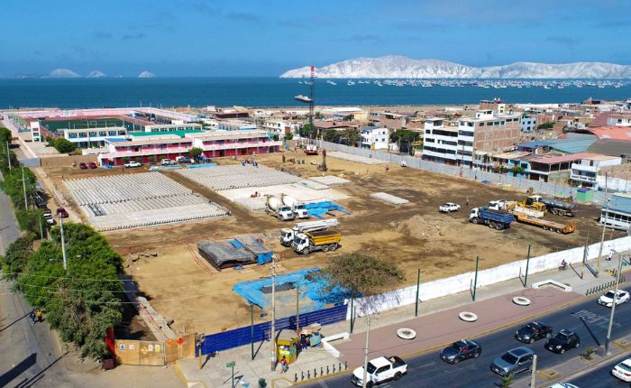 Terreno cercado del Politécnico Nacional del Santa con filas de pilotes, mezcladoras y grúa frente a la bahía