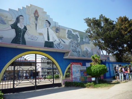 Frontis del instituto Carlos Salazar Romero con el mural de la enfermera y el técnico sosteniendo la antorcha, y el arco azul y amarillo de la entrada.