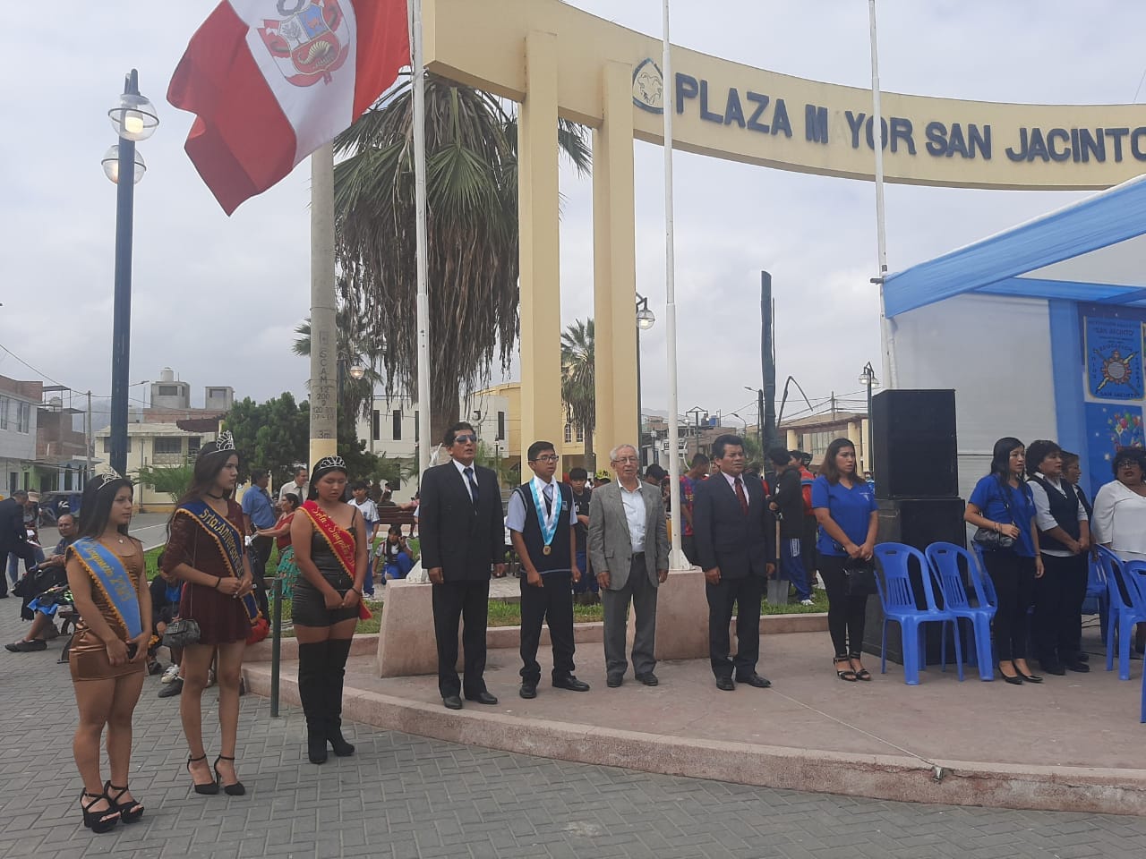 Ceremonia del 61 aniversario en la Plaza Mayor de San Jacinto: autoridades, reinas con banda y estudiantes bajo el arco crema con el nombre de la plaza.