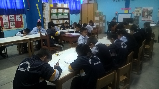 Aula del colegio Víctor Andrés Belaúnde de Chimbote con estudiantes de casaca bordada con el nombre del plantel, en una jornada de trabajo escolar.